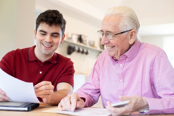 dekorativ, junger Mann hilft Senior beim ausfüllen von Unterlagen