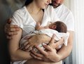dekorativ, Eltern mit Ihrem Neugeborenen im Arm, Mutter stillt