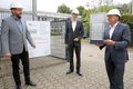 Schulleiter Markus Steinhauer, Projektleiter Franz Steves und Landrat Hans-Jürgen Petrauschke  mit Schutzhelmen stehen mit Abstand vor einem Baustellenschild