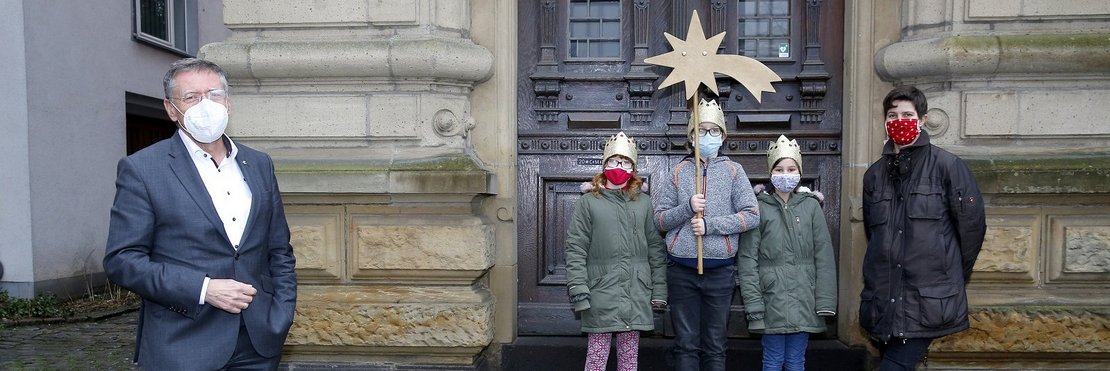 Landrat Petrauschke mit FFP2-Maske steht mit 2 Metern Abstand neben den Sternsingern vor dem Grevenbroicher Ständehaus