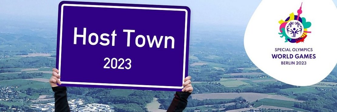 Eine Teilnehmerin der Special Olypics hält ein Schild hoch: Host Town 2023