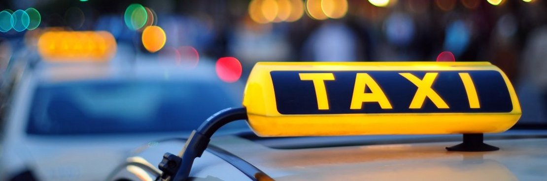 Ein leuchtendes Taxischild auf einem Taxi.