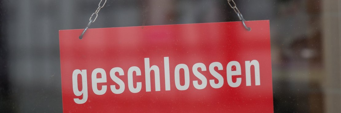 Schild hinter Glasscheibe: Geschlossen