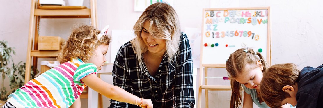 dekorativ, Betreuungsperson mit spielenden Kindern auf dem Boden