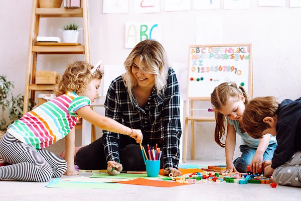 dekorativ, Betreuungsperson mit spielenden Kindern auf dem Boden