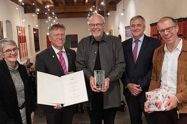 Menschengruppe. Einzelne Personen halten eine Urkunde, Pokal oder ein Geschenk in der Hand.