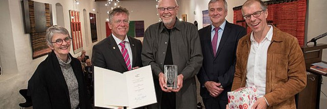 Menschengruppe. Einzelne Personen halten eine Urkunde, Pokal oder ein Geschenk in der Hand.