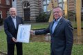 Landrat Petrauschke überreicht Kallen vor dem Ständehaus in Grevenbroich die Urkunde für den Sportehrenamtspreis des Rhein-Kreises Neuss