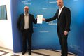 Bert Römgens und Kreisdirektor Dirk Brügge halten gemeinsam jedoch mit Abstand ein Schriftstück