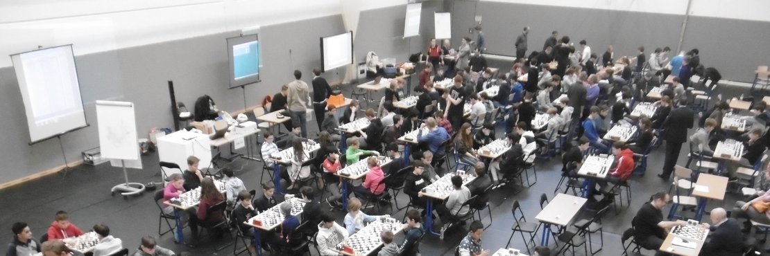In der Halle der International School on the Rhine in Neuss stehen mehrere Tischreihen mit schachspielenden Kindern.