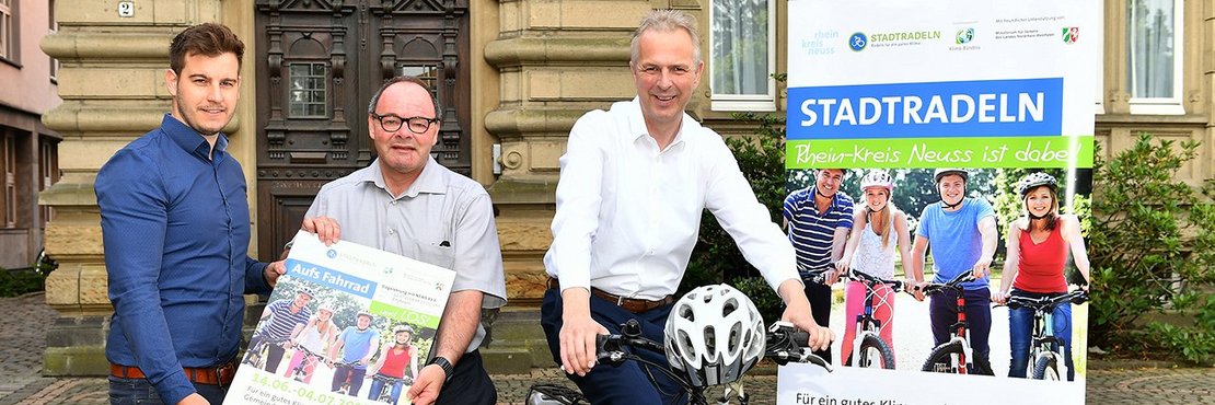 Drei Personen mit Plakat und Fahrrad