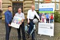 Drei Personen mit Plakat und Fahrrad