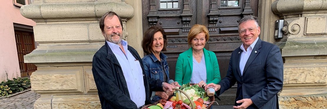 Landrat Hans-Jürgen Petrauschke, Juliane Wahode, Helga Kradepohl und Wolfgang Wappenschmidt stehen mit einem Erntedankkorb vor dem Ständehaus in Grevenbroich. 