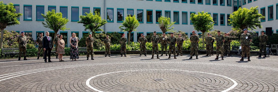 Landrat Petrauschke Kreisgesundheitsamtsleiterin Albrecht stehen mit mehr als 20 Soldat*innen und zivilen Mitarbeitenden der Bundeswehr versetzt mit Abständen vor dem Kreishaus in Grevenbroich