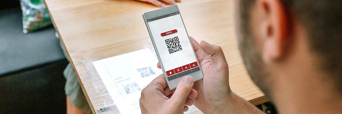 Symbolbild: Person scannt QR Code mit Smartphone