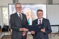 Landrat Hans-Jürgen Petrauschke und Hans Scholten halten eine Urkunde