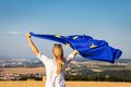 Eine Frau hält mit ausgestreckten Armen eine wehende Europafahne über Ihren Kopf.
