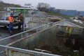 Zwei männliche Personen werfen Restabfälle in einen Container auf einer Deponie