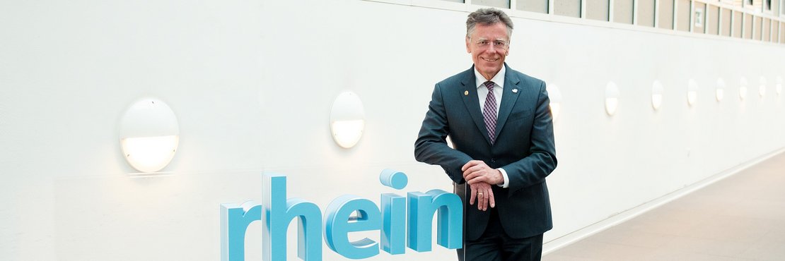 Landrat Hans-Jürgen Petrauschke lehnt an einem blauen 3-D-Logo des Rhein-Kreises Neuss