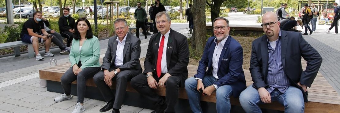 Lena Agop, Landrat Hans-Jürgen Petrauschke, Edelbert Jansen, Harald Vieten und Jens Kotterba sitzen auf einer Bank vor einem Baum