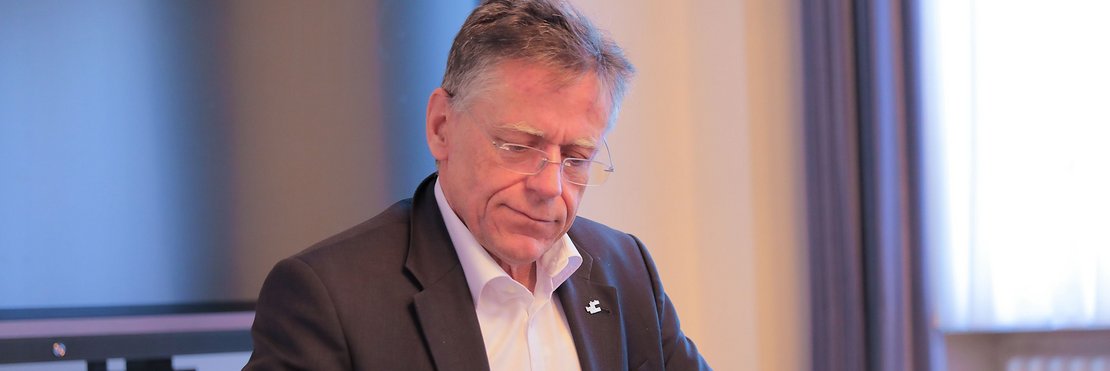 Landrat Hans-Jürgen Petrauschke sitzt arbeitend an einem Tisch