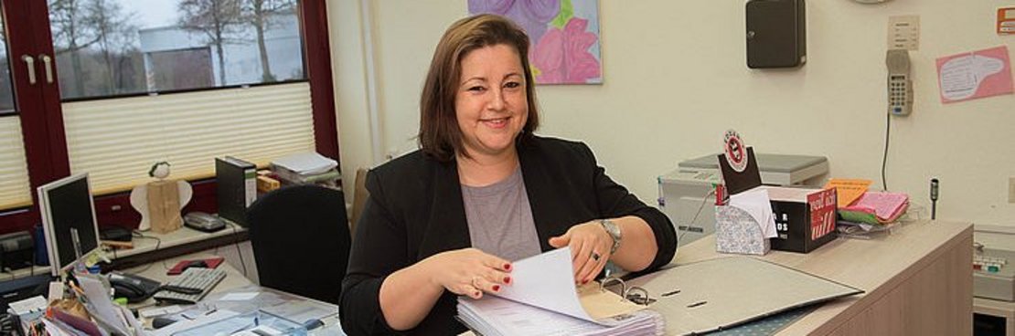 Birgit Brehmer sitzt arbeitend an einem Schreibtisch