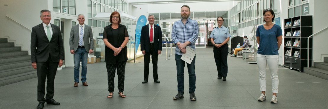 Landrat Hans-Jürgen Petrauschke, Stephan Vetten, Jutta Winkler, Klaus Schirm, Jens Päuser, Daniela Luppus und Julia Vieten stehen mit Abstand im Lichthof des Kreishauses Neuss