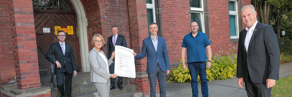 Raimund Franzen, Ulrike Groth, Landrat Hans-Jürgen Petrauschke, Prof. Dr. Jürgen in der Schmitten, Marcus Mertens und Kreisdirektor Dirk Brügge stehen mit Abstand zueinander vor dem roten Backsteinhaus des Technologiezentrum Glehn 