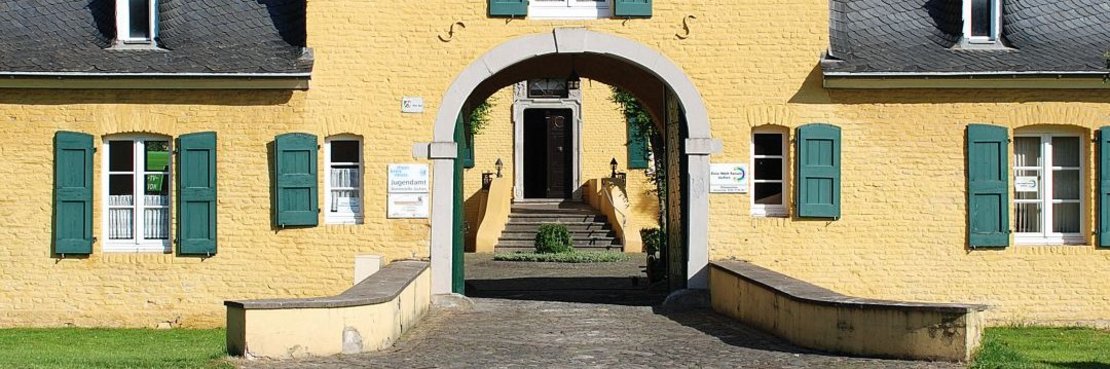 Historisches Gebäude mit Torbogen in gelb mit grünen Fensterläden