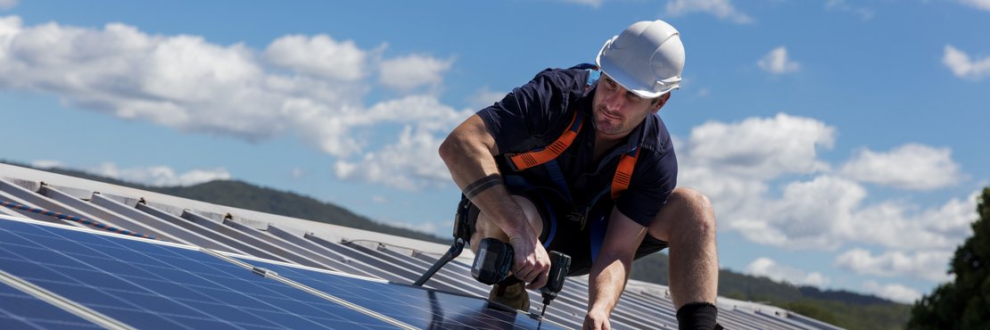 Ein Mann befestigt Solarzellen auf einem Dach