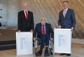 Herr Fischer, Herr Dr. Klose (im Rollstuhl) und Landrat Petrauschke halten zwei große Bilderrahmen mit den Dankes-Urkunden
