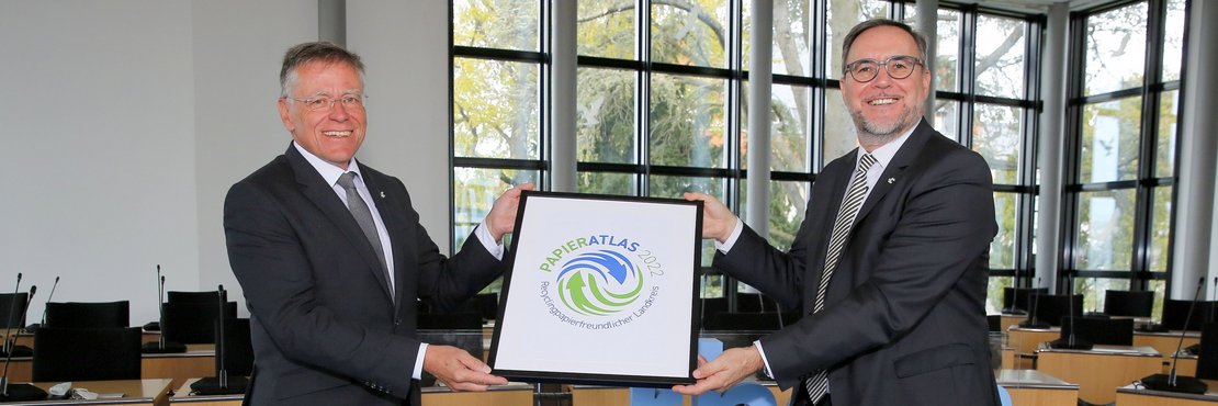 Foto von Landrat Hans-Jürgen Petrauschke und der zuständige Dezernent Harald Vieten mit der Auszeichnung „Recyclingpapierfreundlicher Landkreis 2022“.