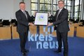 Foto von Landrat Hans-Jürgen Petrauschke und der zuständige Dezernent Harald Vieten mit der Auszeichnung „Recyclingpapierfreundlicher Landkreis 2022“.
