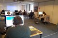 Mehrere Personen sitzen mit Headsets vor Bildschirmen