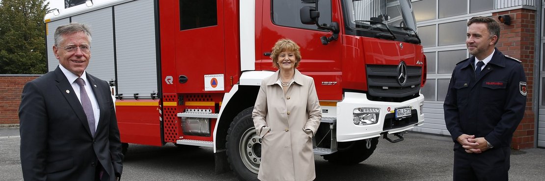 Landrat Hans-Jürgen Petrauschke, Bürgermeisterin Angelika Mielke-Westerlage und Tim Söhnchen stehen mit großen Abständen voneinander vor dem neuen Feuerwehrfahrzeug.