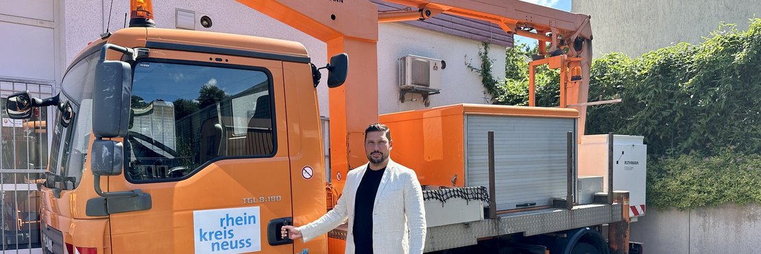 Orangefarbener LKW mit großem ausfahrbarem Arm mit Arbeitskorb