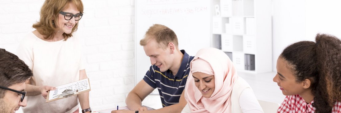 Menschen verschiedener Nationen sitzen arbeitend an einem Tisch