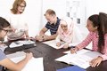 Menschen verschiedener Nationen sitzen arbeitend an einem Tisch