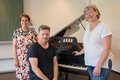 Drei Personen vor einem Klavier