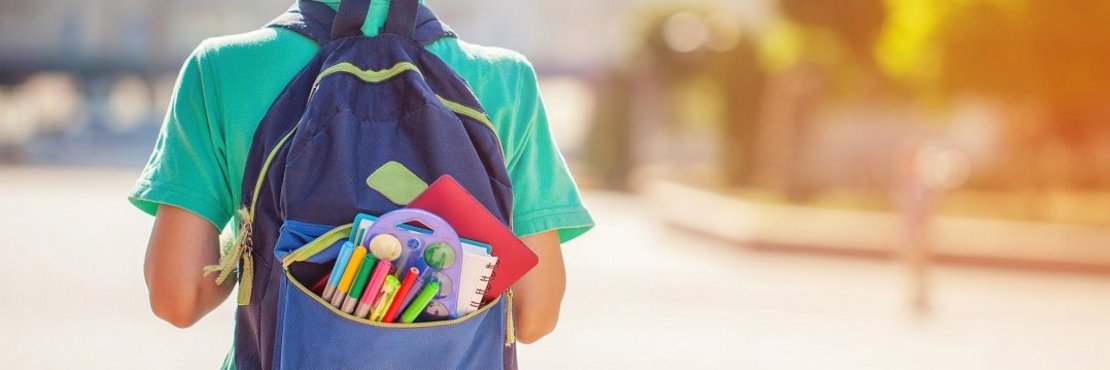 Ein Junge mit einem gefüllten Schulrucksack.