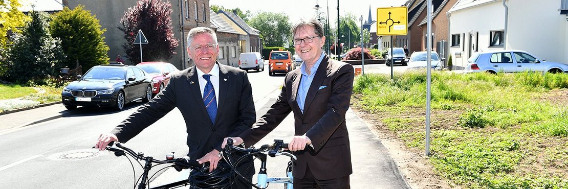  Landrat Hans-Jürgen Petrauschke (links) und Dezernent Karsten Mankowsky stehen mit Fahrrädern auf dem neuen Radweg