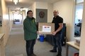 Fabian Fox und ein Vertreter der Firma Auch GmbH halten gemeinsam einen Karton