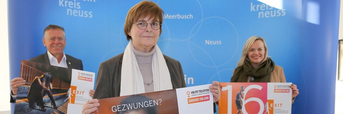 Die in der Bildbeschreibung genannten Personen stehen mit Abstand vor einem blauen Fotohintergrund und halten Kampagnen-Plakate hoch. 