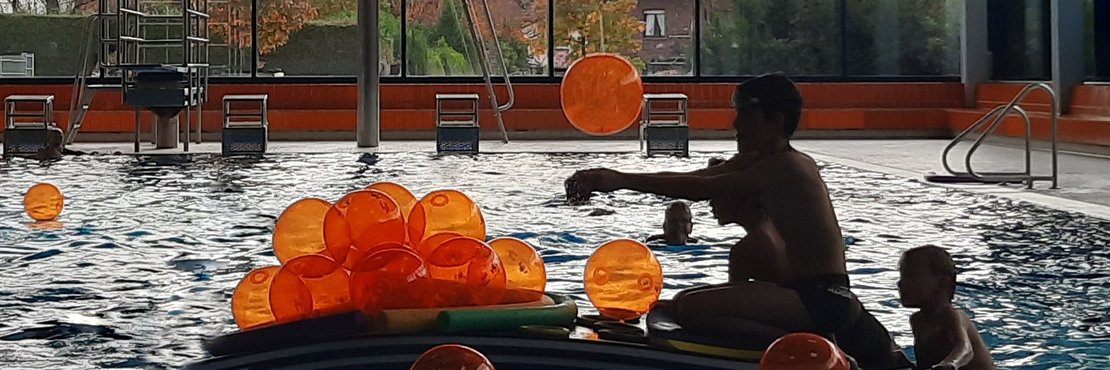 Kinder im Schwimmbad mit orangenen Wasserbällen