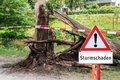 Symbolbild: Warnschild "Sturmschaden" vor abgeknicktem Baum