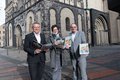 Landrat Hans-Jürgen Petrauschke, Tourismusförderin Steffi Lorbeer und Robert Abts stehen auf einem Platz und halten den Kultur- und Freizeitführer in der Hand