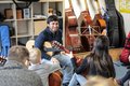 Männliche Person mit Gitarre vor einer Gruppe Kindern