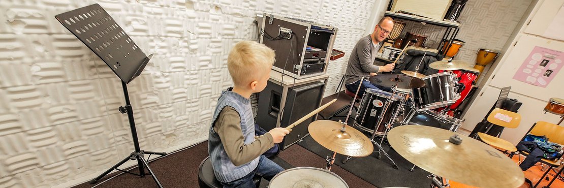 Junge am Schlagzeug mit Musiklehrer