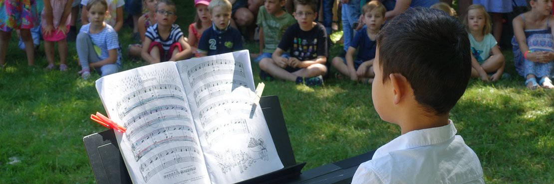 Kind sitzt am Klavier vor Publikum