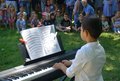 Kind sitzt am Klavier vor Publikum